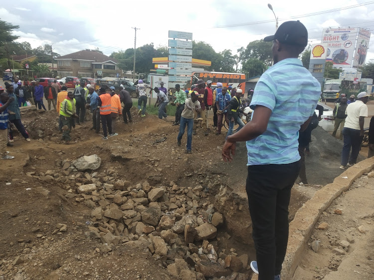 Township MCA Andrew Kimani leads Thika traders and boda boda riders in refilling the trench at Bonjour roundabout.