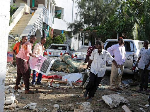 Men carry a body at the scene of an attack outside a hotel and an adjacent restaurant in Mogadishu, Somalia June 15, 2017. /REUTERS