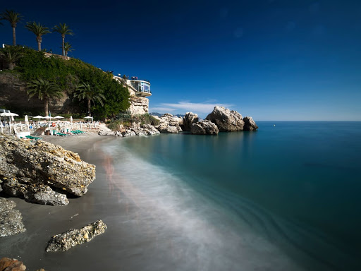 a beach with umbrellas and chairs along the shore