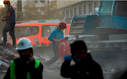 A worker holds a national flag as rescue operations take place on a site after an earthquake struck the Aegean Sea, in the coastal province of Izmir, Turkey on November 2 2020. 