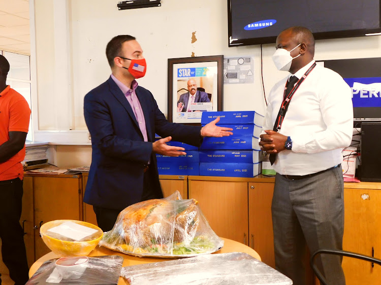 Information Officer/Press Attache' Andrew Veveiros offers turkey to the Head of Content Radio Africa Paul Ilado to celebrate thanksgiving on November 25, 2021.