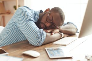 Taking a break. Tired afro american man in glasses sleeping at his working place at home. Afro