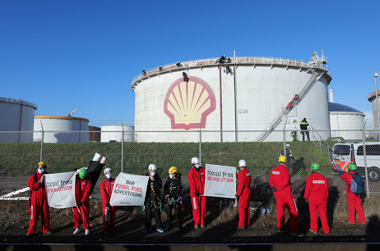 Environmental activist groups including Greenpeace are seen climbing a Shell oil tank to protest against "greenwashing" advertisements in Rotterdam, Netherlands, on October 4 2021. Picture: REUTERS/EVA PLEVIER