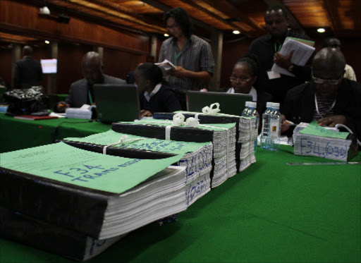 Judiciary officials and political parties’ agents involved in the petition challenging the results of the March 4 presidential election scrutinise the 33,400 Forms 34 used at 22 polling stations, at KICC in Nairobi on Wednesday.