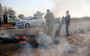 Police put out fires during an anti-zama zama protest in Westonaria on Wednesday.
