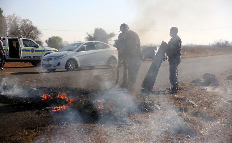 Police put out fires during an anti-zama zama protest in Westonaria on Wednesday.