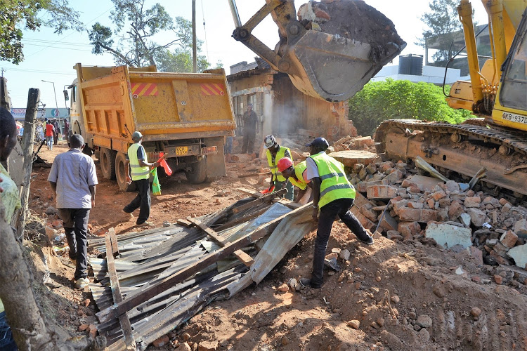 A government bulldozer removes the rubble of kiosks brought down in Kitui town. An MCA is among three people suspected of stealing another in August in Matinyani.