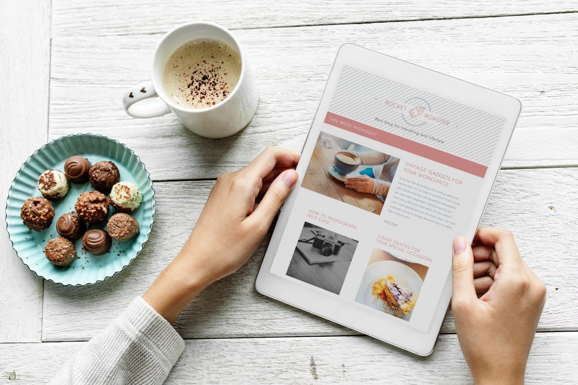 Person Holding White Tablet Beside White Ceramic Mug