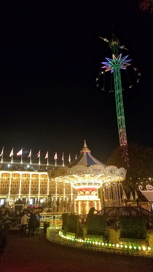 The Star Flyer is the high swing carousel ride in the back right, and the the Swing Carousel to the left from 1907 used at Halloween and Christmas / Visiting Tivoli Amusement park during Halloween decoration time, October 2018