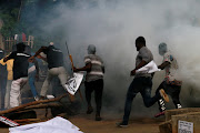 Protesters run after police fired teargas during a June 12 Democracy Day rally in Abuja, Nigeria on June 12, 2021. 