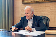 US President Joe Biden, who tested positive for Covid-19 while experiencing mild symptoms, sits at his desk in the White House residence in this handout photo obtained from President Biden's Twitter account on July 21, 2022. 