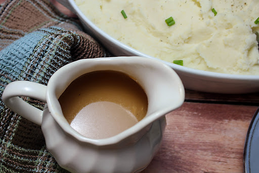 Gravy in a gravy boat with mashed potatoes.