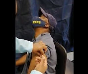 A police officer reacting with fear when receiving his vaccine.