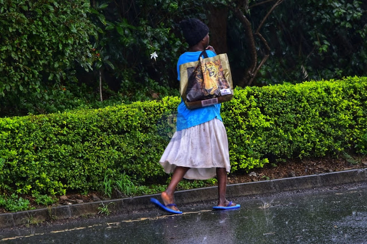 A woman walking in the rain on Friday along Oloitoktok Road, Kileleshwa