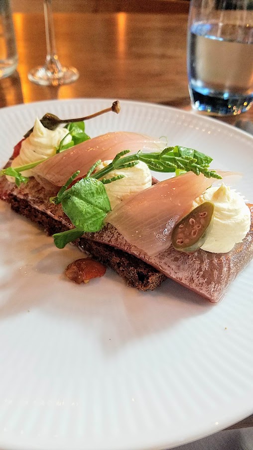 Restaurant Palaegade in Copenhagen offering traditional Danish smørrebrød of Red pickled herring with rosehips, creme fraiche, and pickled onion