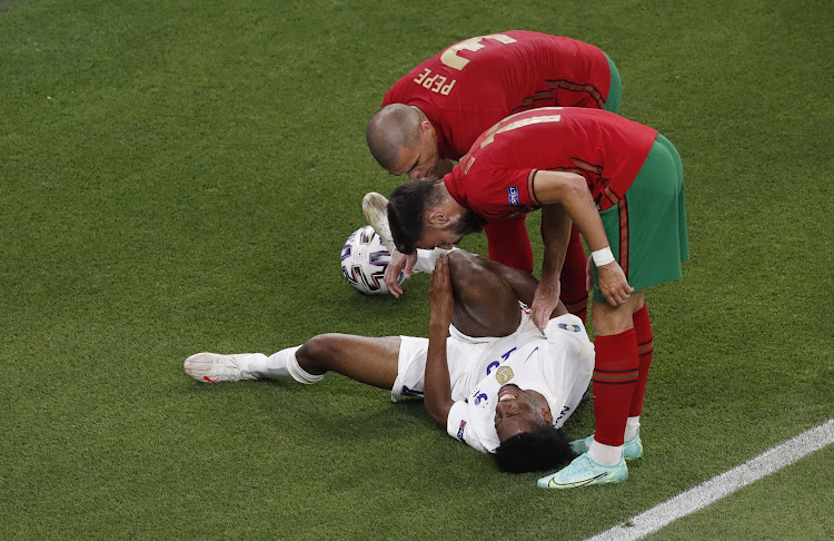 France's Kingsley Coman after sustaining an injury as Portugal's Bruno Fernandes and Pepe look on