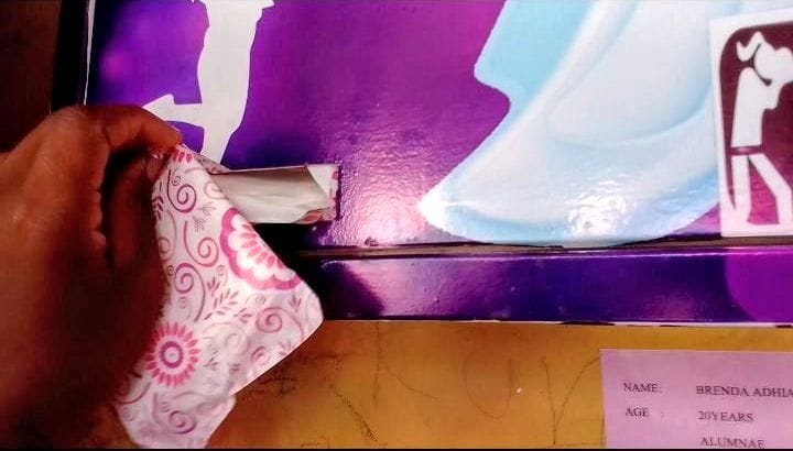 A girl picks one sanitary pad from the dispenser.