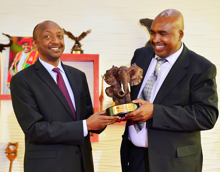 Rwandan High Commissioner to Kenya Richard Masozera receives a gift from MKU founder and chairman Simon Gicharu at the university's main campus in Thika on Tuesday, April 24.