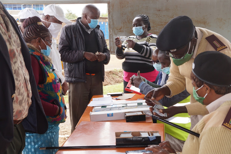 Lari deputy county commissioner Agnes Karoki checks a Huduma Card as civil registry officials and chiefs crosscheck details at Nyambare on Wednesday