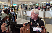 Bafana Bafana coach Hugo Broos is interviewed by the media as the team arrive at OR Tambo International Airport on March 29 2023 from their Africa Cup of Nations qualifying win against Liberia.