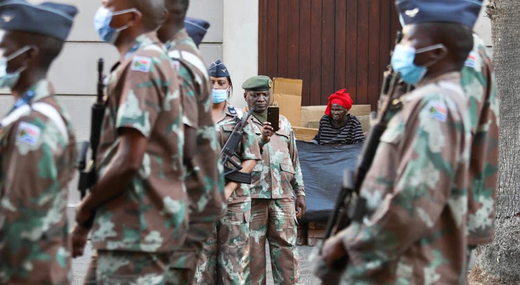 A homeless woman looks on as final rehearsal preparations take place ahead of Thursday's state of the nation address at the Cape Town city hall.