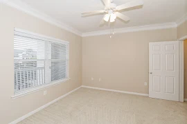 Bedroom with tan walls and tan carpet facing window