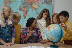 A teacher teaching kids geography with the help of a globe