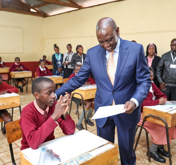 President William Ruto hands a KCPE candidate his examination papers at Kikuyu Township Primary School, Kiambu on October 31, 2023