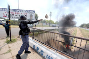 Members of the police clear barricades outside Hoerskool Overvaal in Vereeniging on the second day of protests there. Police have been removing barricades and monitoring the violent protest.