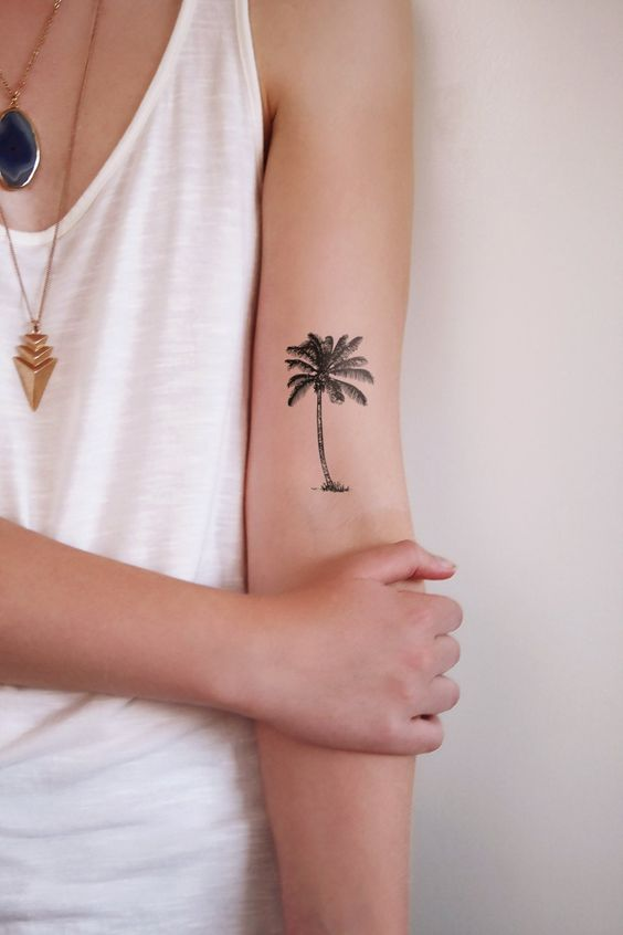 Lady shows off her palm tree tat  on her arms 