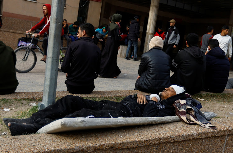 A wounded Palestinian man sleeps in front of the emergency section of Nasser hospital in Khan Younis in the southern Gaza Strip, December 10 2023. Picture: IBRAHEEM ABU MUSTAFA/REUTERS