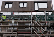 A crane lifts up a pre-fabricated, insulated facade element made by Berlin-based firm Ecoworks which will be attached to the outside of an older building, in Bochum, Germany, November 8, 2022. 