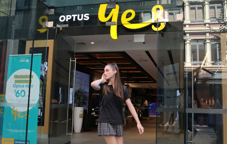 A woman uses her mobile phone as she walks past in front of an Optus shop in Sydney, Australia, in this file photograph. Picture: REUTERS/DANIEL MUNOZ