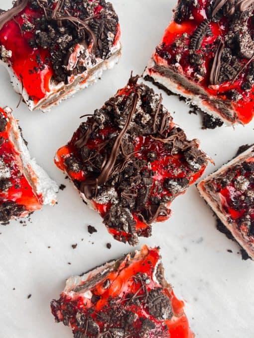 Squares of no bake strawberry chocolate dessert.