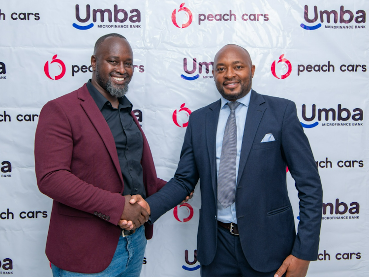 Martin Mugo, Branch Manager at Peach Cars shakes hands with Alvan Gesaka, Senior Credit Officer at Umba Microfinance Bank after siging the car financing deal, May 2, 2024.
