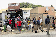 BLIND EYE: Police officers stroll away from a crowd looting a shop in White City, Soweto yesterday. In an official statement, the South African Police Service said that its officers were taking strong action and would not allow lawlessness to prevail