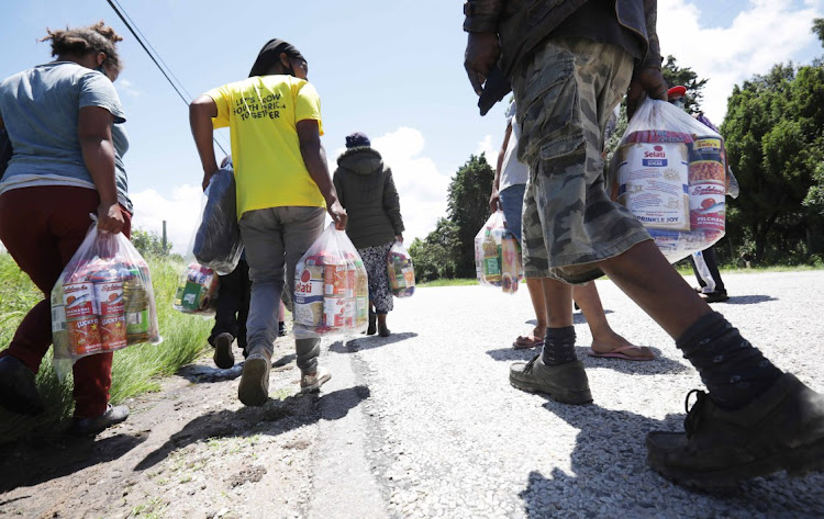 Residents of Wilderness Height informal settlement walk back to their homes after they received aid from the Gift of the Givers team.