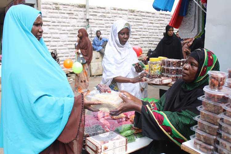 A vendor Fatma Tatu selling goods to a customer as they celebrate Eid Mubarak outside Jamia mosque, Nairobi on April 10, 2024
