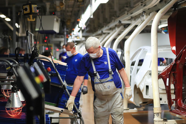 Assembly line workers wear protective face masks as Volkswagen restarts production at its headquarter factory in Wolfsburg, Germany, on Monday