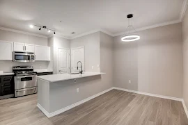 Modern apartment kitchen with white cabinetry, stainless steel appliances, and a breakfast bar.