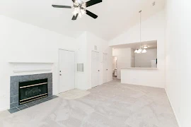 Living room features light carpet, light walls, fireplace with dark tile surround and overlooks front door and two closets