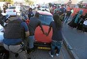 An officer searches men in Parkwood on the Cape Flats on Wednesday, when Cape Town Metro Police conducted operations in the area.