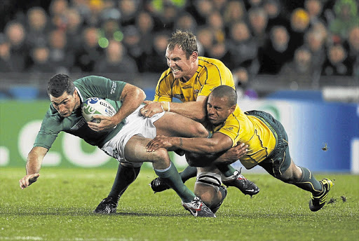 Wallabies Rocky Elsom, top, and Will Genia tackle Ireland's Rob Kearney during the World Cup Pool C match at Eden Park yesterday Picture: REUTERS