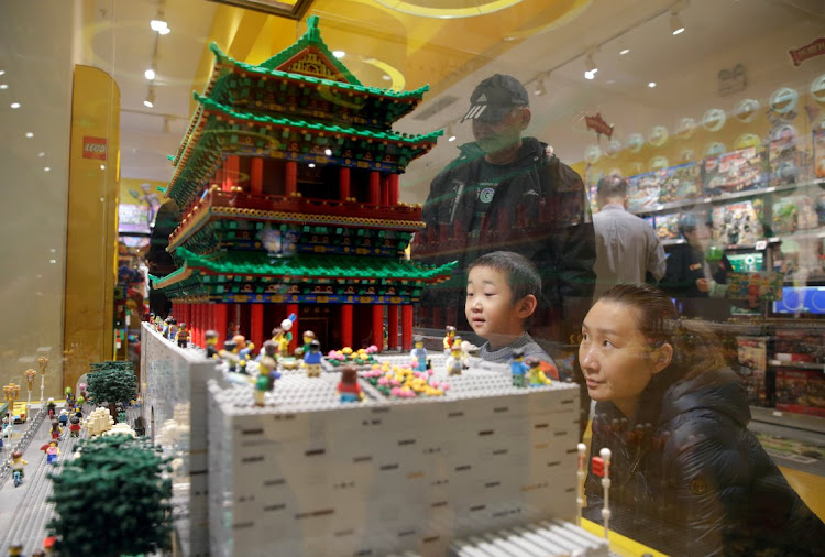 A boy and his mother look at the Zhengyang Gate Tower of Forbidden City made with Lego bricks at a Lego store in Beijing, China.