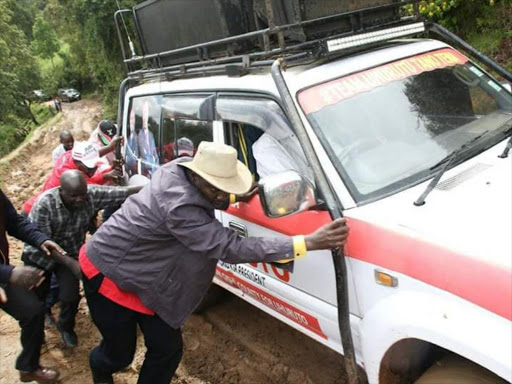 Uasin Gishu Governor Jackson Mandago helps to push a car stuck in mud during campaigns in Elgeyo Marakwet, October 16, 2017. /MATHEWS NDANYI