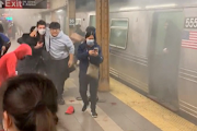 A person helps an injured man after a shooting at a Brooklyn subway station, in New York City, New York, US April 12, 2022