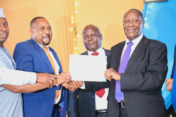 Kitui governor Julius Malombe hands a certificate to Finance executive Peter Kilonzo after his department came second in performance appraisal