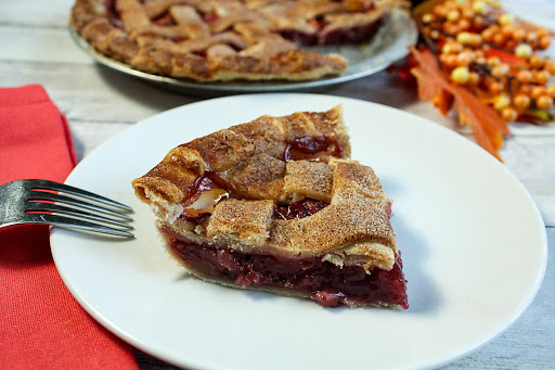 A slice of apple cranberry pie on a plate.