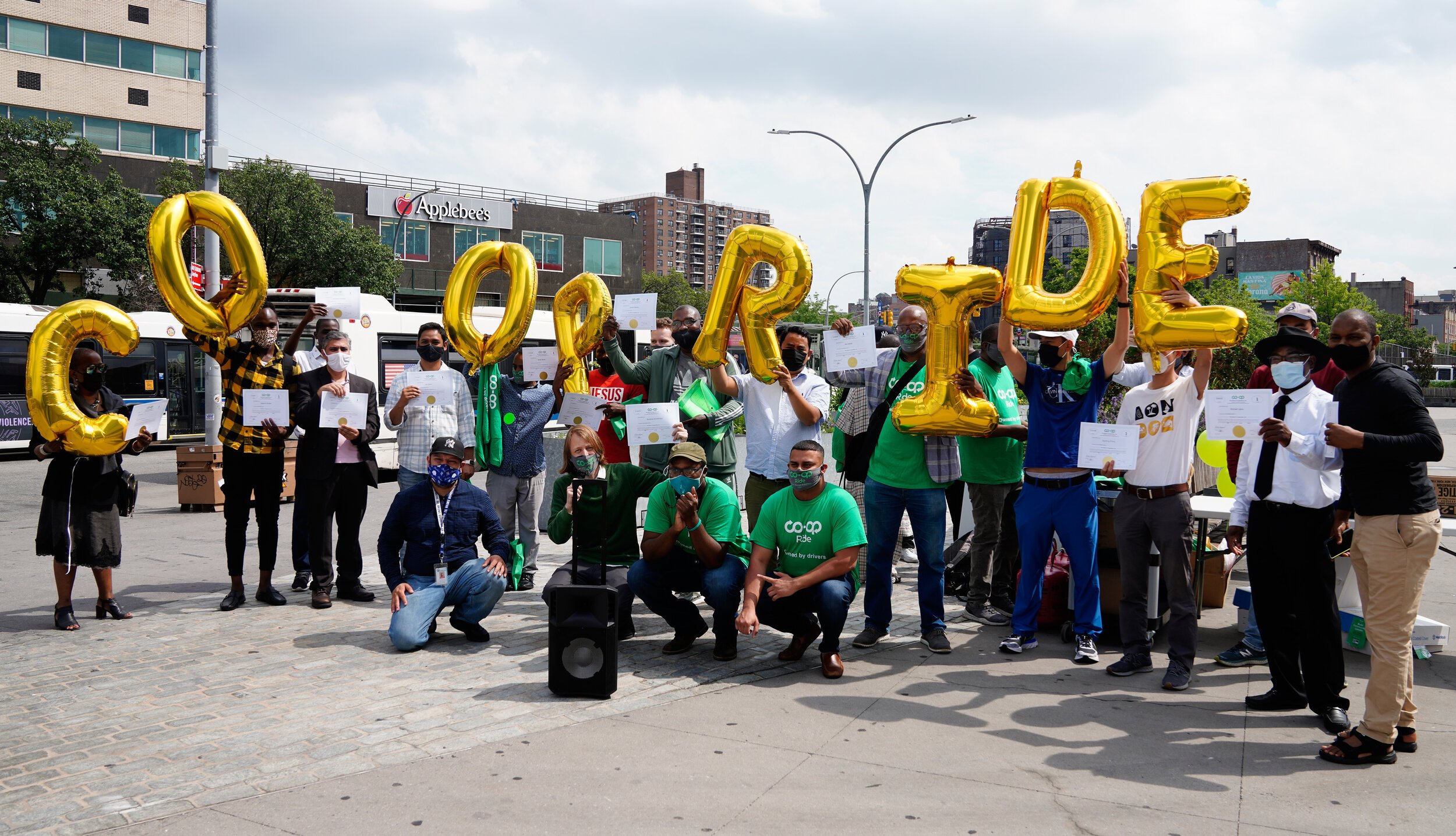 A group photo of the Drivers Cooperative team holding balloons that read "Co-op Ride". 