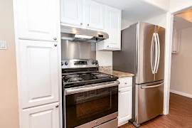 Kitchen with stainless steel appliances, white cabinets, and stone-inspired countertop